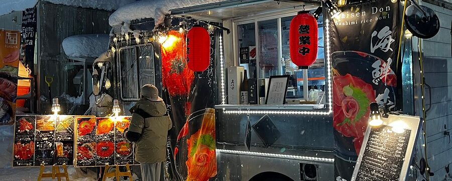Snowy food truck park in Niseko Japan at night serving ramen, wagyu skewers, and local beers during BSSC group ski trip