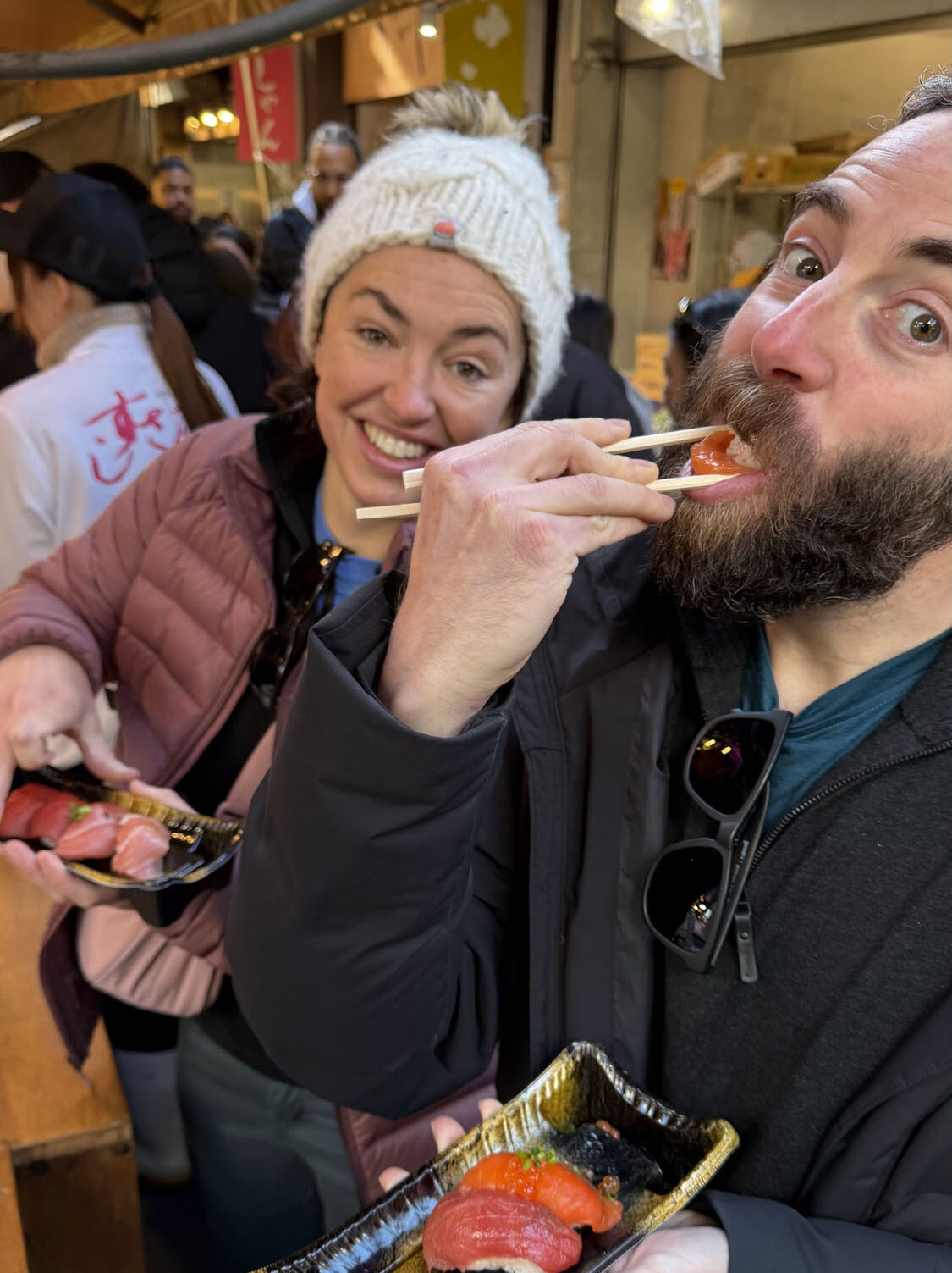 BSSC travelers tasting fresh sushi and seafood at Tokyo Tsukiji Fish Market during Japan ski trip, capturing local food culture.