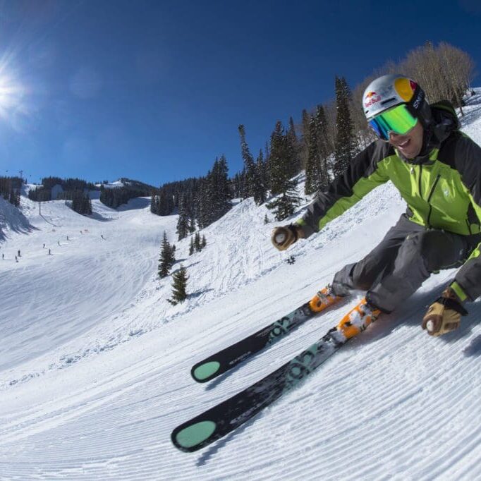 Chris Davenport skiing down fresh corduroy on a steep snow covered groomed slope in the mountains at Aspen Mountain Ski Resort in Colorado